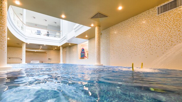 Une grande piscine intérieure dotée d’une zone d’observation avec un plancher en verre située au-dessus.