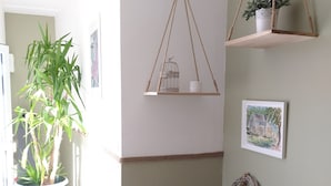 Une pièce avec une table en bois, une plante suspendue, un tableau encadré et une plante en pot.