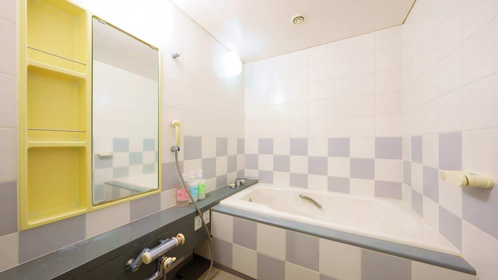 Une salle de bain avec une baignoire, un miroir et une étagère jaune.