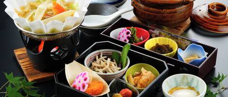 A variety of dishes and bowls on a table, including rice, noodles, and other food items.