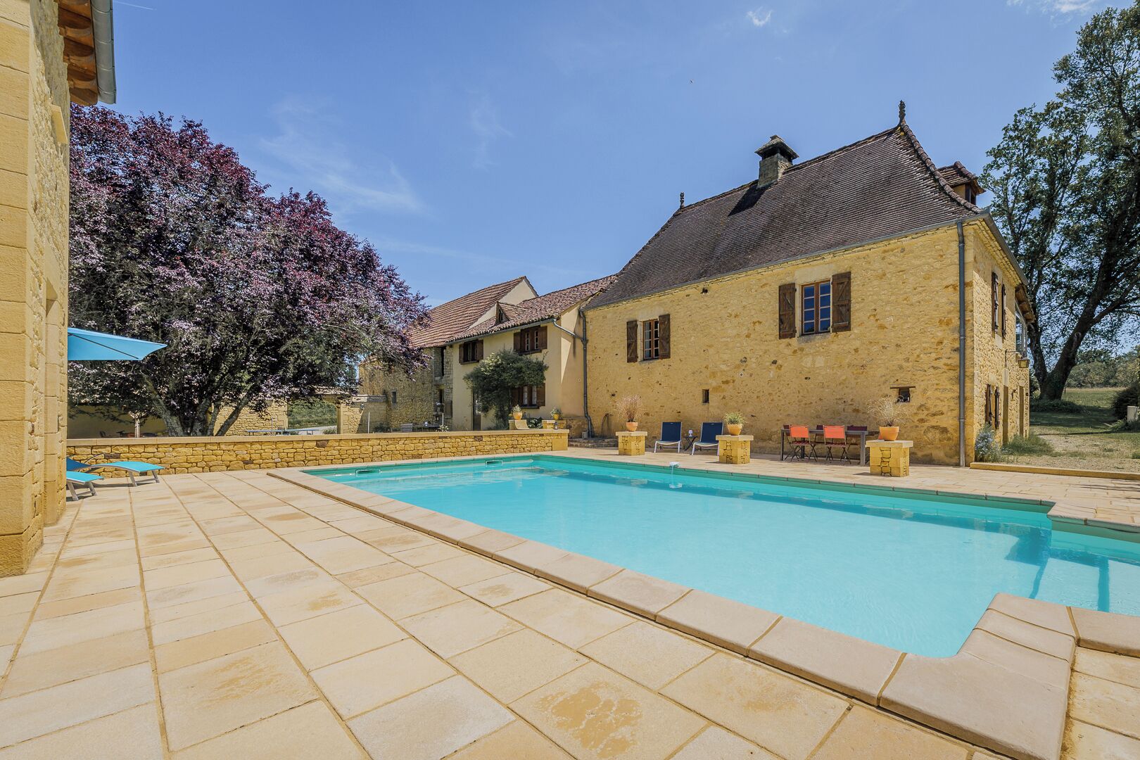 A stone building with a swimming pool and outdoor seating.