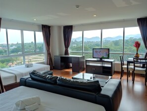 A hotel room with a large bed, a sofa, a desk, and a TV. There are large windows with a view of the outdoors. - The Living Hills (Chiang Mai)
