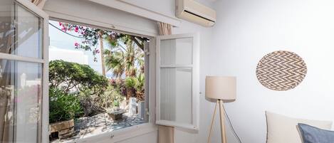 Une pièce dotée d’une grande fenêtre, d’un climatiseur, d’un lampadaire et d’un lit avec des oreillers.