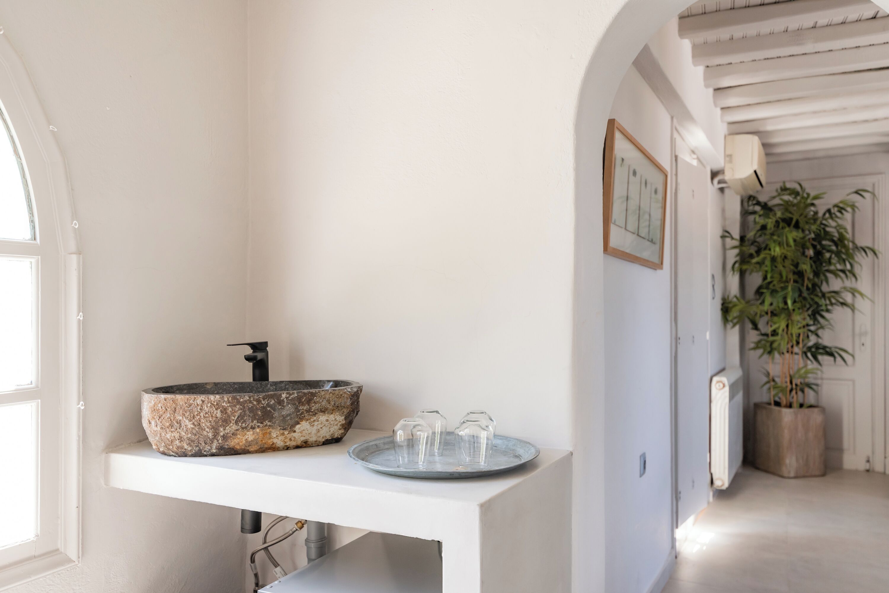 A bathroom with a stone sink, a small table, and a potted plant.