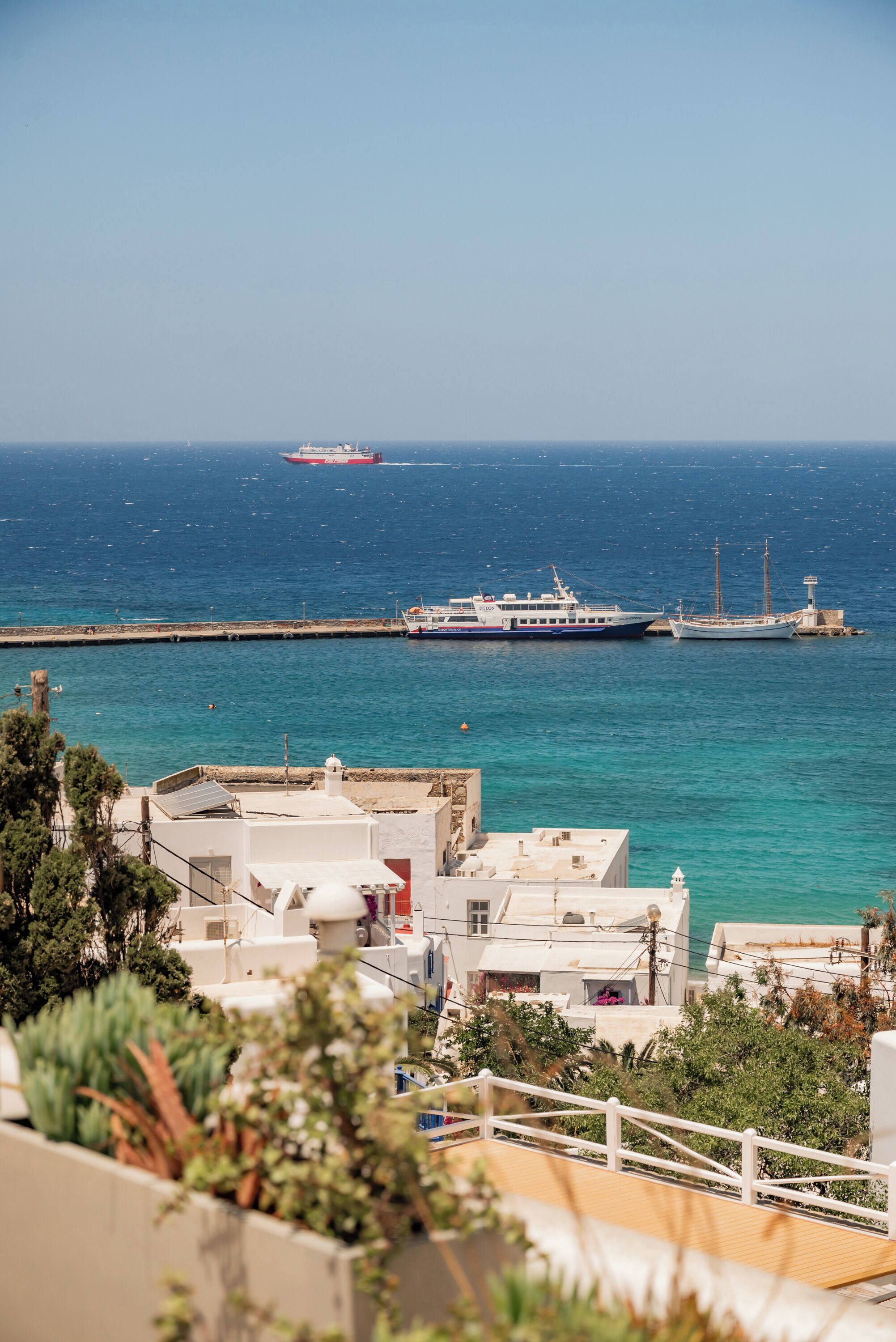 Uma vila costeira com um cais, barcos e edifícios com varandas voltadas para o mar.