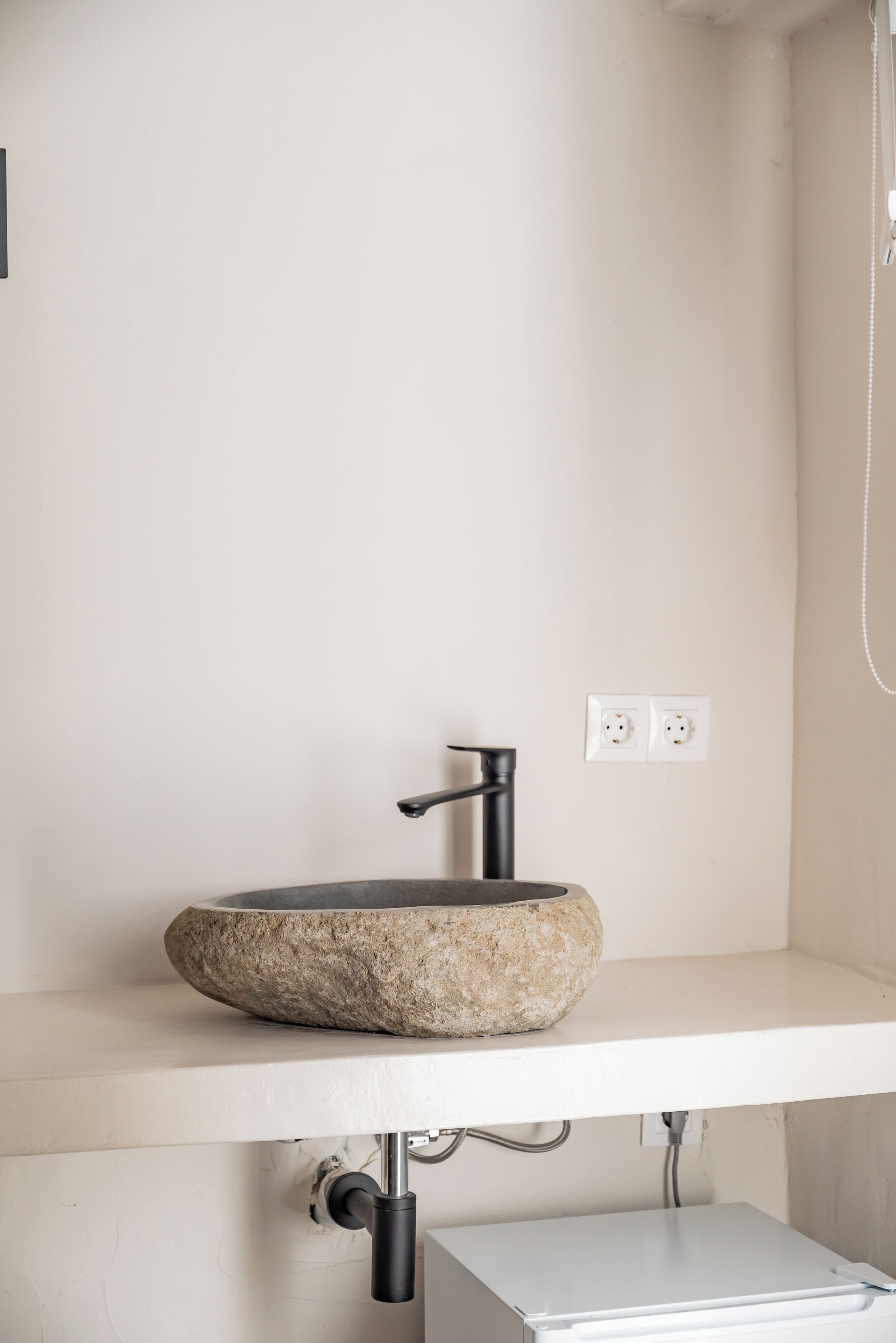 Ein Badezimmer mit einem SteinklopfZiegel, einem modernen Wasserhahn und einer weißen Arbeitsplatte.