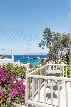 A balcony with a view of the sea, a white railing, and a table with chairs. - Rania Apartments Sea View (Mykonos)