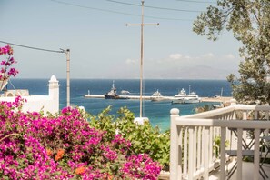 A coastal view with a white building, a lighthouse, and boats in the harbor. - Rania Apartments Sea View (Mykonos)