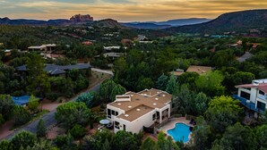 A modern two-story house with a large backyard and a swimming pool, surrounded by lush greenery and hills in the background. - Sedona Spectacular: Luxury 3BR home with private pool, hot tub, and stunning red rock views. (Sedona)