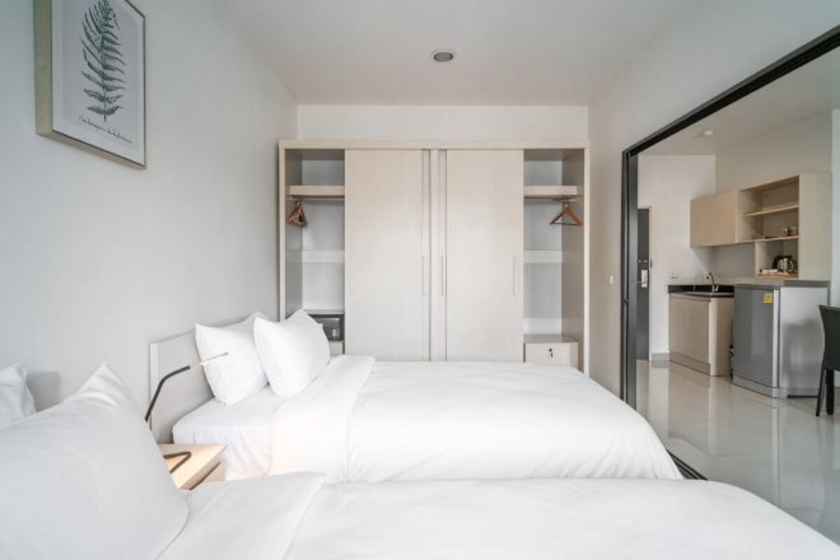 Une chambre d’hôtel moderne dotée d’un grand lit, d’un dressing et d’une kitchenette.