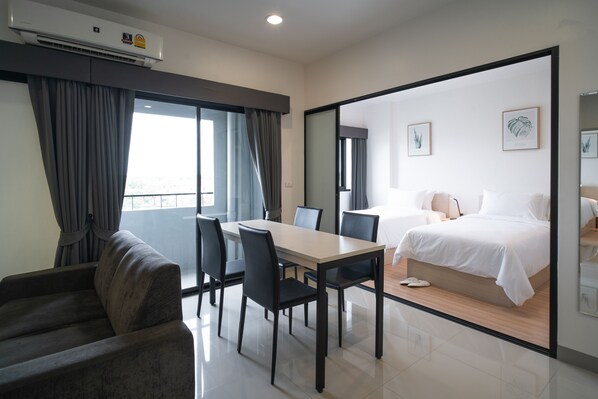 A modern hotel room with a balcony, a dining area, and a bed. - KOS Hotel Suvarnabhumi Airport (Bangkok)