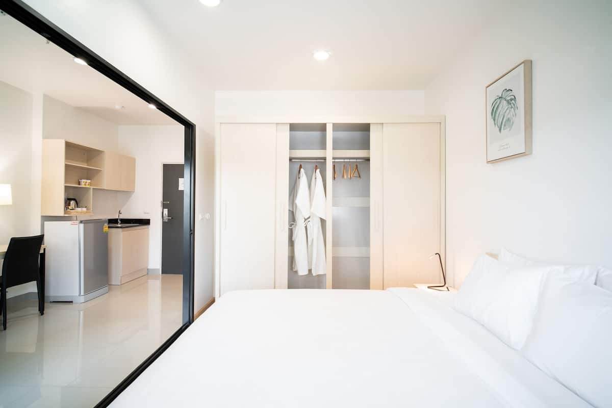 Habitación de hotel con cama, armario, kitchenette y baño.