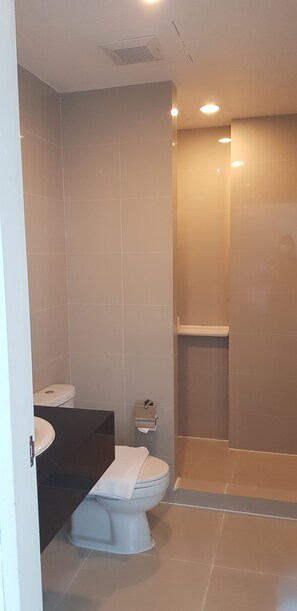 A modern bathroom with a toilet, sink, and glass-enclosed shower. - KOS Hotel Suvarnabhumi Airport (Bangkok)
