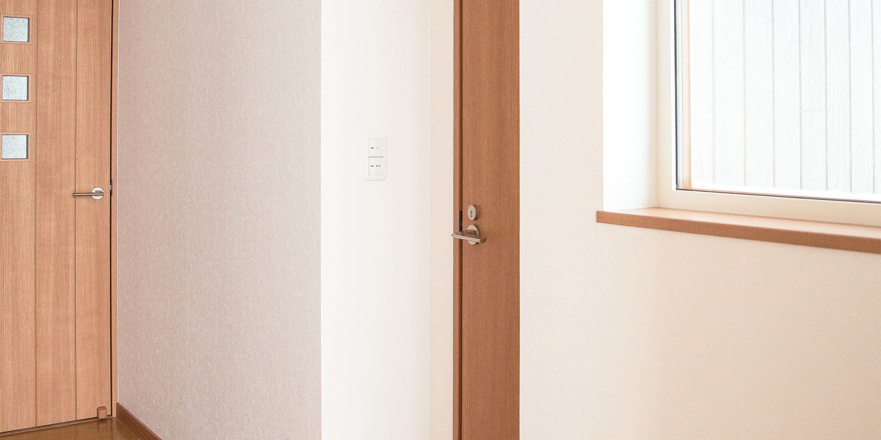 Une pièce avec une porte en bois, un mur blanc et une fenêtre avec des stores.