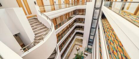 Interior de un hotel con varios niveles, un atrio central y una zona de piscina.