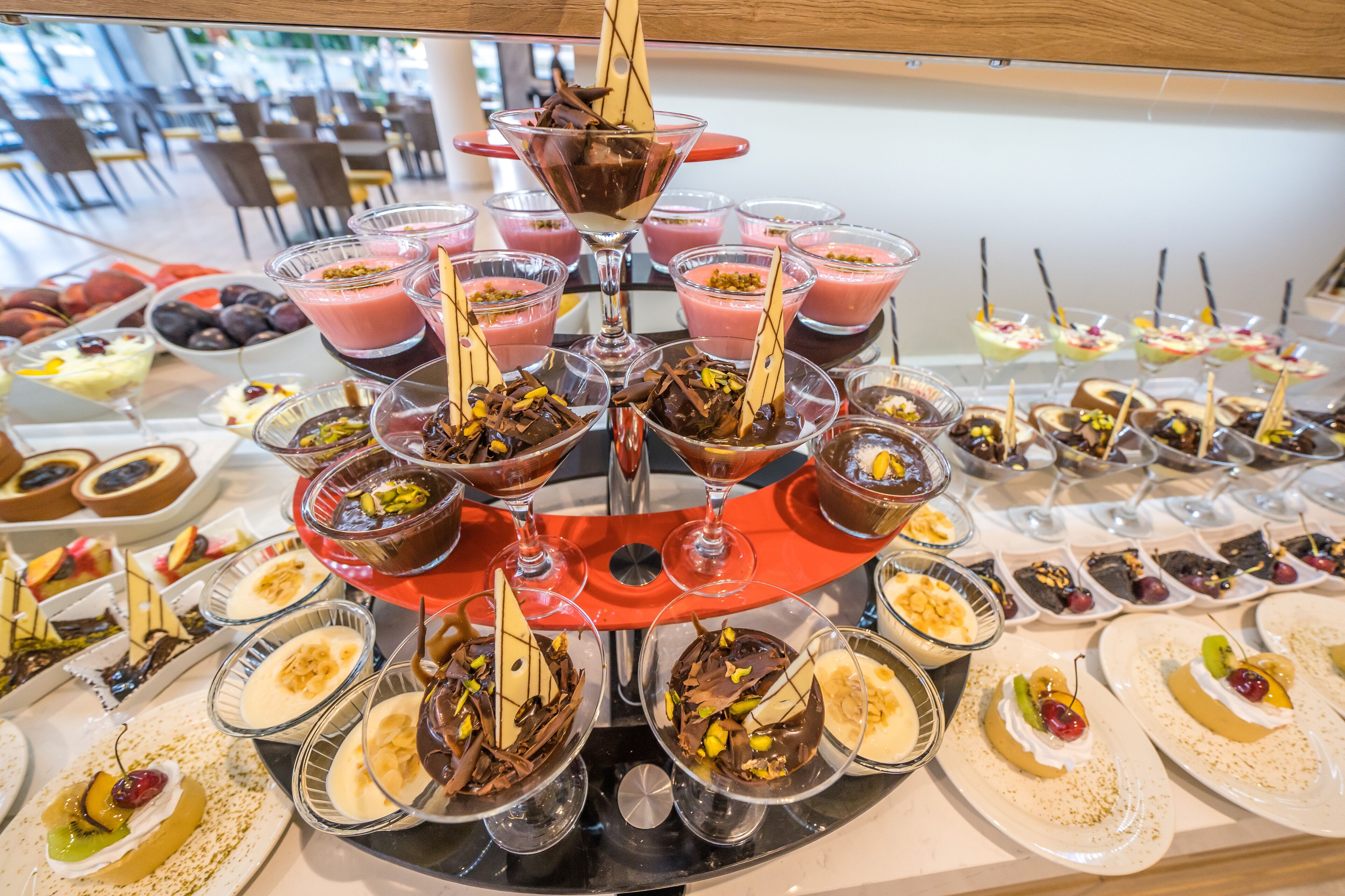 Un bufé con diversos postres y bebidas dispuestas en un soporte escalonado.