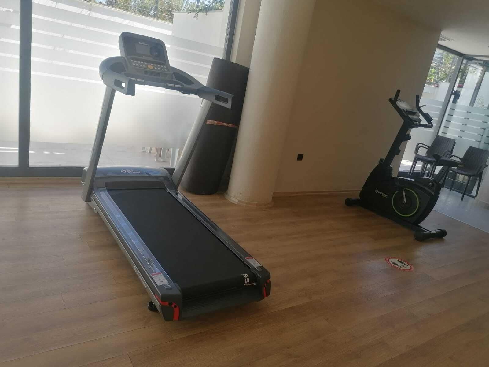 Una habitación con cinta de correr, elíptica y bicicleta estática.