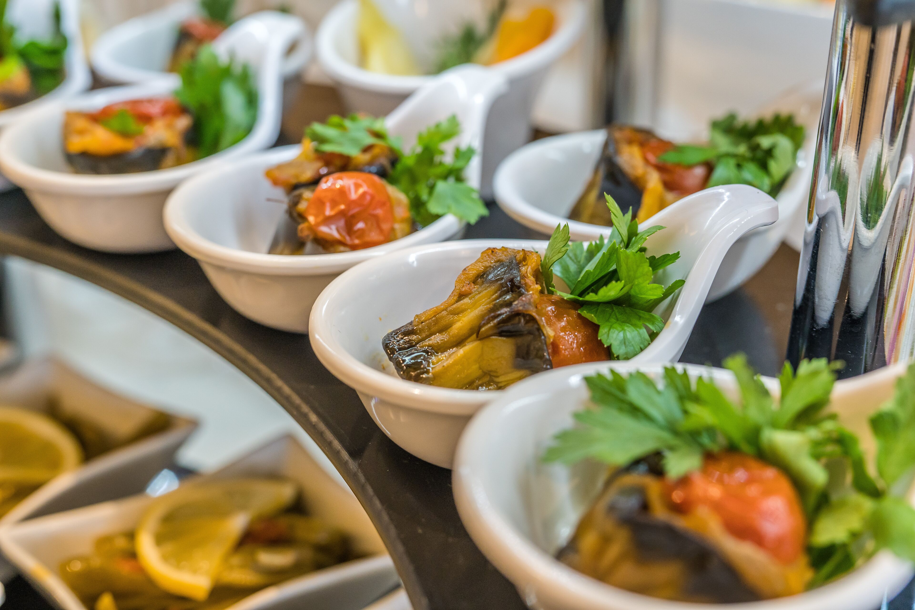 Une table de buffet proposant divers plats, notamment des fruits de mer et des légumes, présentés dans des plats blancs.