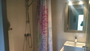 Une salle de bain avec une douche, un lavabo et un miroir.