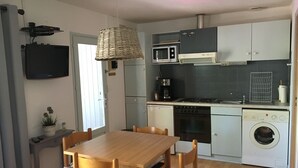 Une cuisine compacte comprenant une table et des chaises, un four à micro-ondes, une cuisinière, un four et un lave-linge.