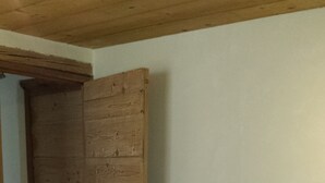 Una habitación con cama, puerta de madera y paredes blancas.