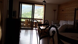 Una habitación con techo de madera, una cama con cubrecama blanco, una silla, una mesa y vistas a un balcón con barandilla de madera y una mesa.