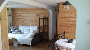 Una habitación acogedora con una cama, una mesita con un cuenco metálico y una pared de madera.