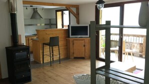 Una cocina acogedora con una isla de madera, un televisor y un hogar de leña.