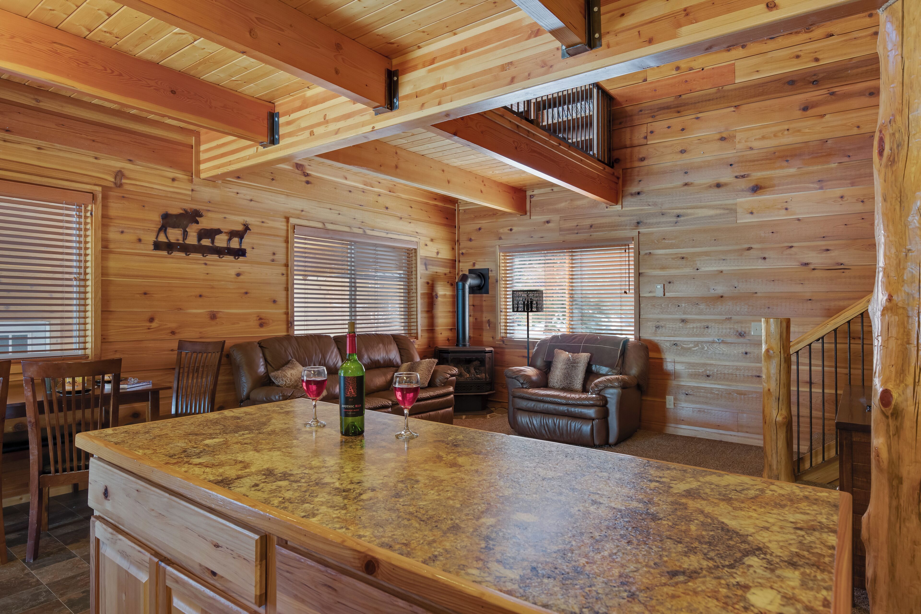 A wooden cabin interior with a large kitchen island, wooden walls, and a fireplace.