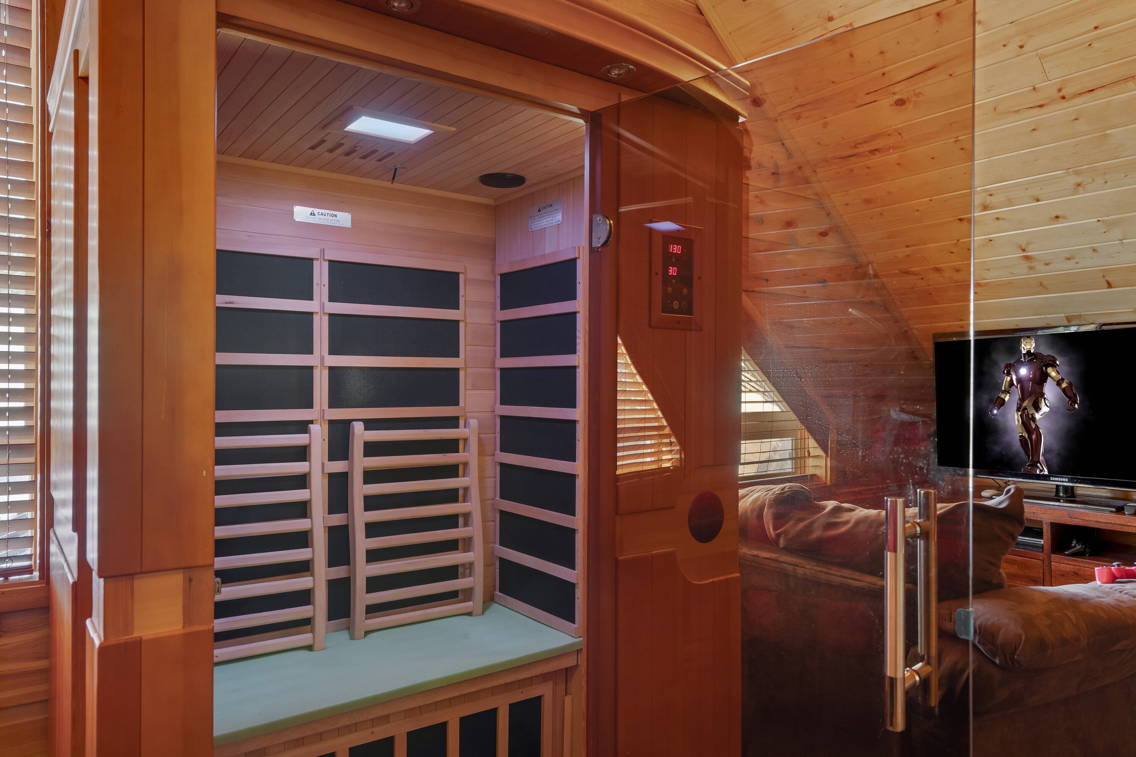 A wooden cabin with a small seating area, a television, and a ceiling-mounted control panel.