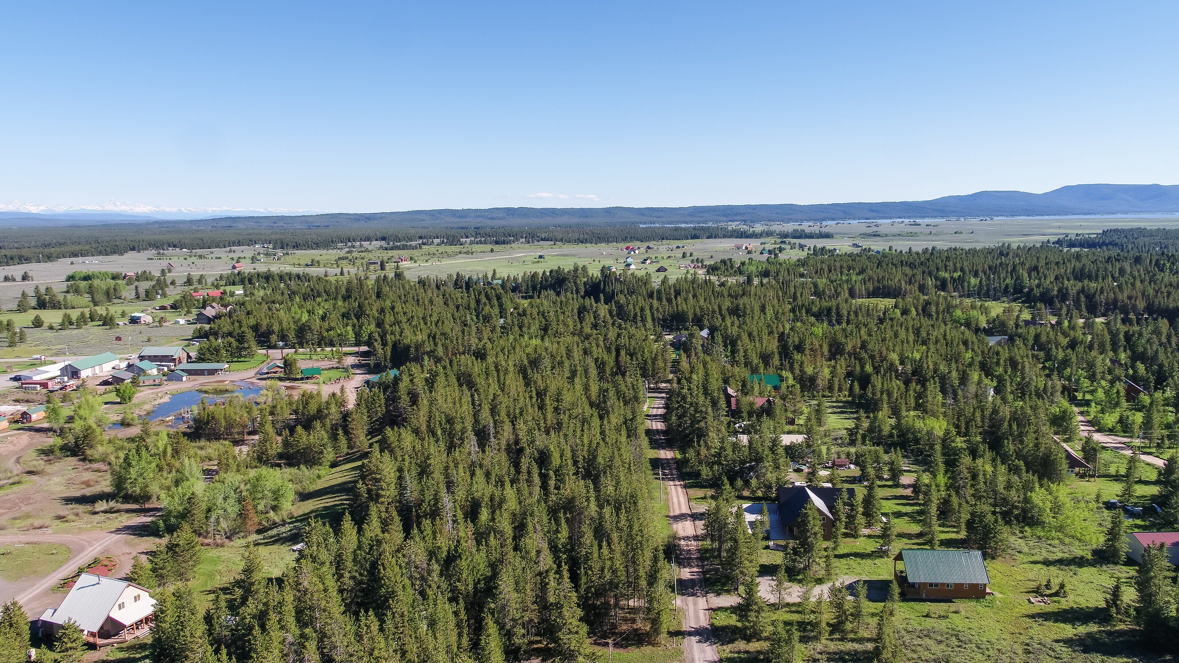 A rural area with scattered houses, a small lake, and dense forest.