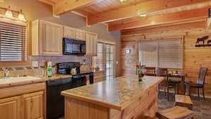 A kitchen with wooden cabinets, a microwave, a stove, and a large island. - Rimfire Refuge (Island Park)