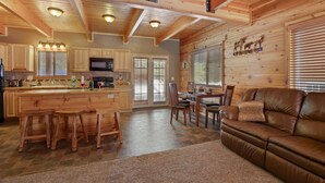 A spacious kitchen with wooden cabinets, a central island with stools, and a dining area with a leather couch. - Rimfire Refuge (Island Park)