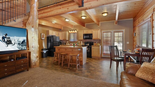 A spacious kitchen with wooden cabinets, a central island, and a dining area with chairs. - Rimfire Refuge (Island Park)
