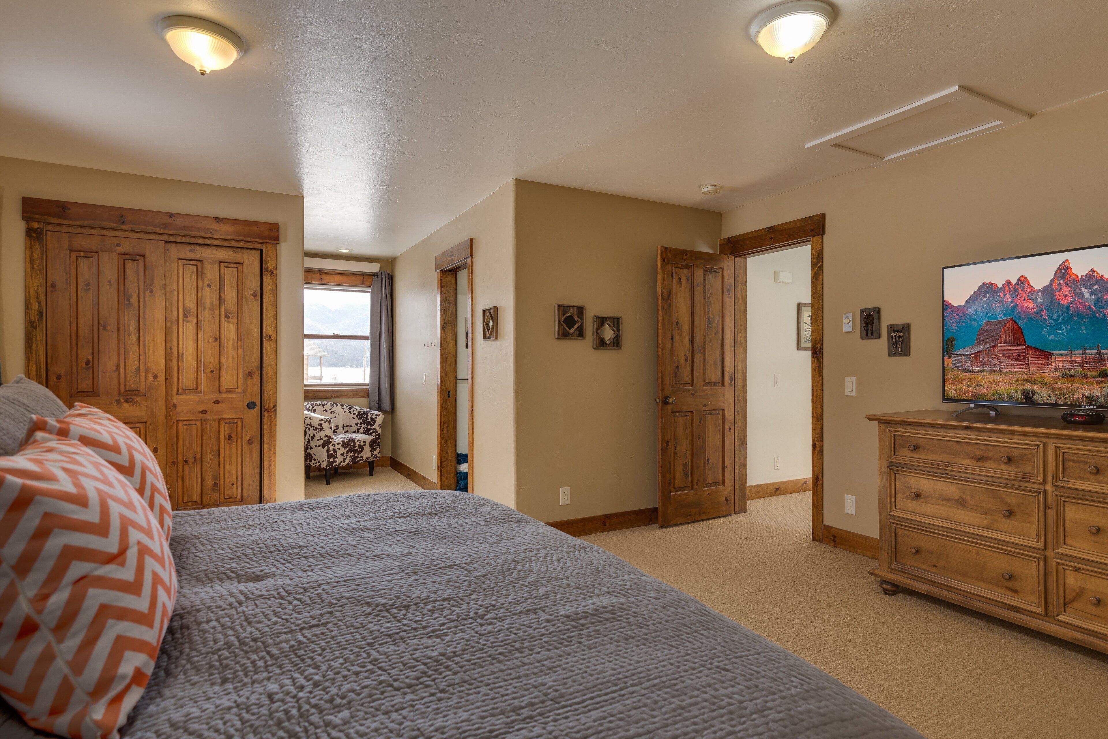 Ein Schlafzimmer mit einem großen Bett, einem Holzschrank und einem Fernseher auf einer Kommode.