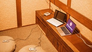 Una habitación con una estantería de madera que muestra un juego de Super Mario, una computadora portátil y un arreglo floral.
