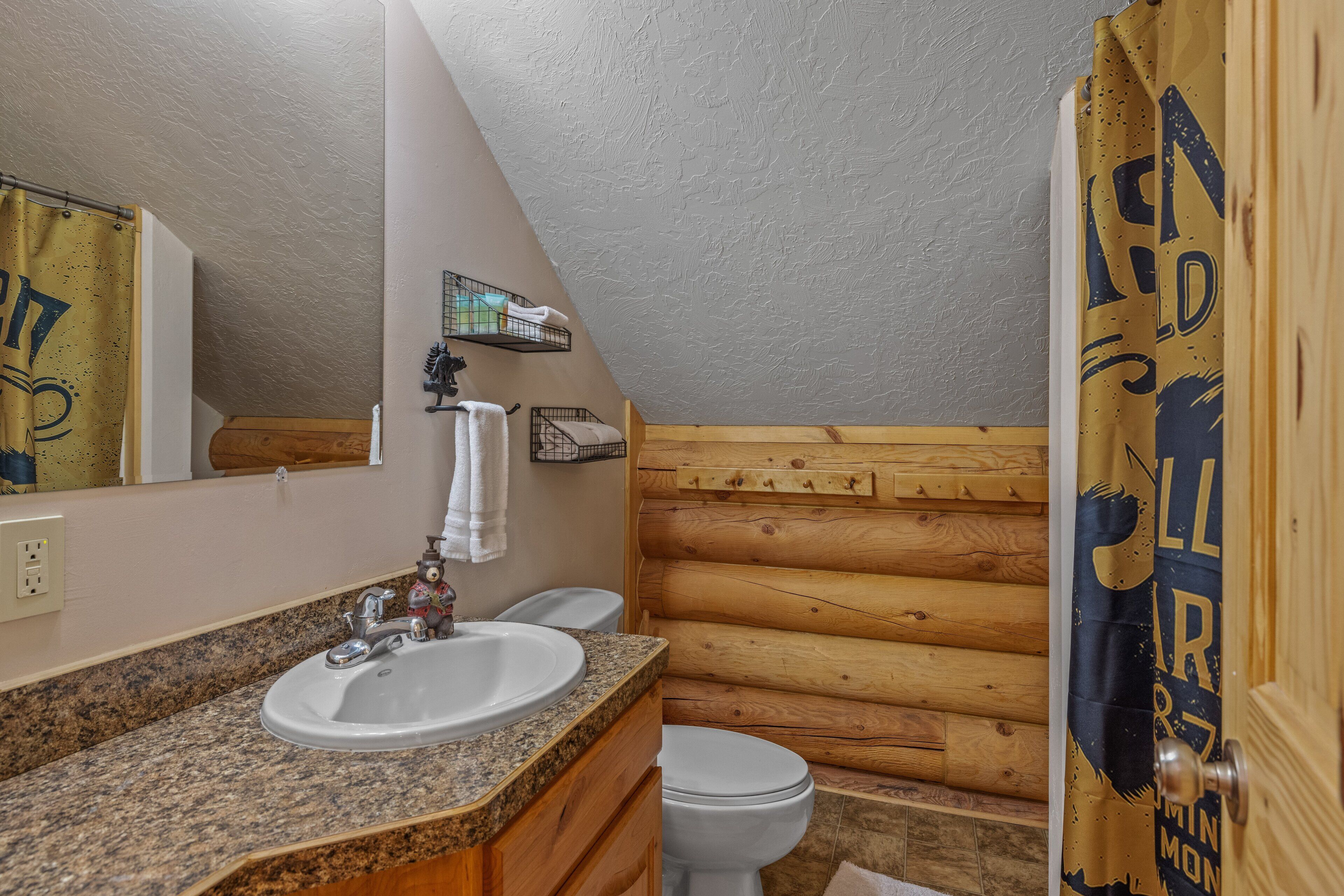 A bathroom with a granite countertop sink, white toilet, and wooden walls.
