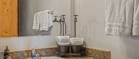 Un baño con encimera de granito, un lavabo, un espejo, un perchero para toallas y un calentador de toallas.
