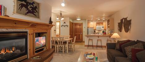 Una sala de estar acogedora con chimenea, televisor, comedor y cocina.