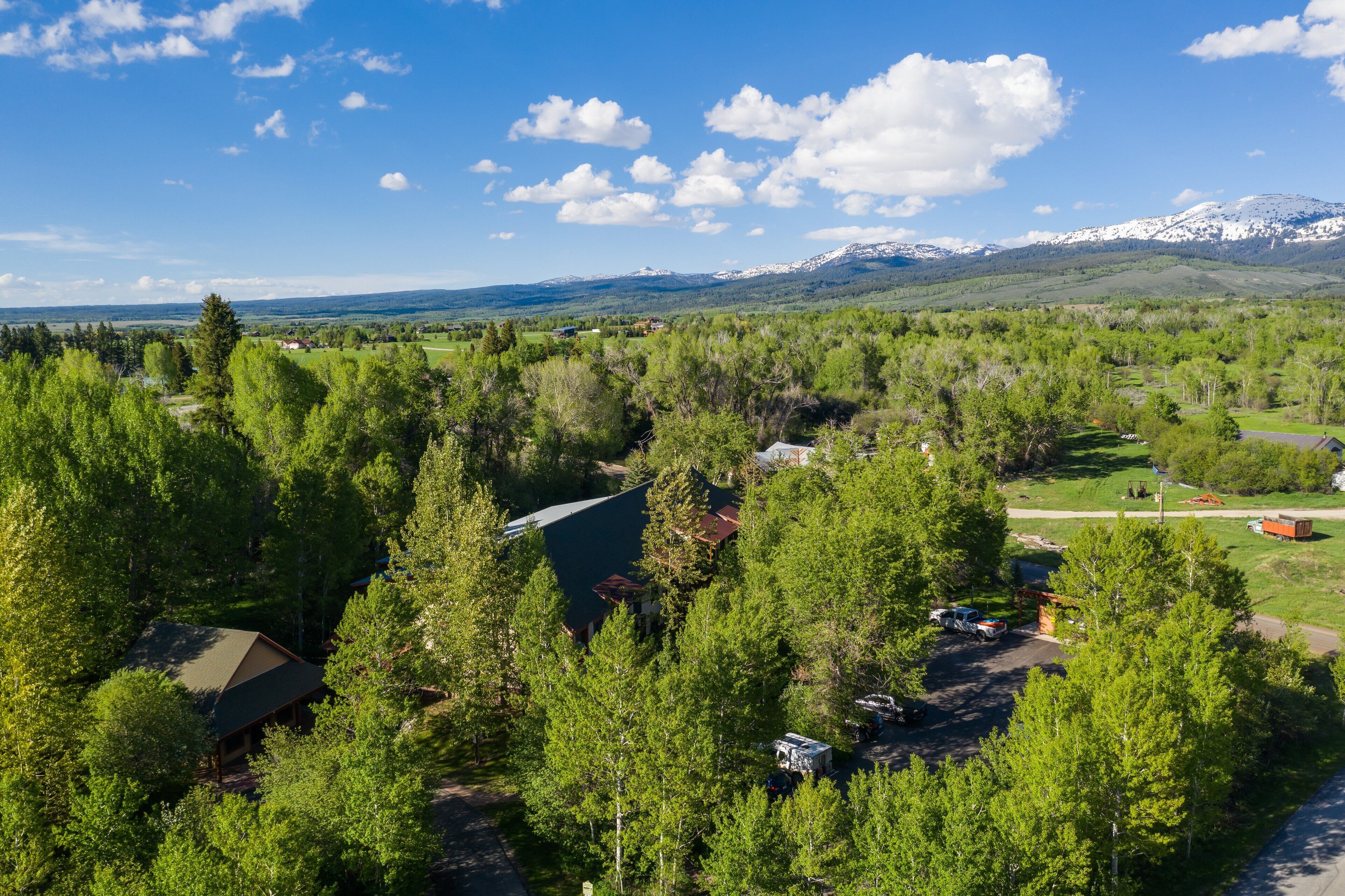 A lodge surrounded by dense forest with a mountain range in the background.