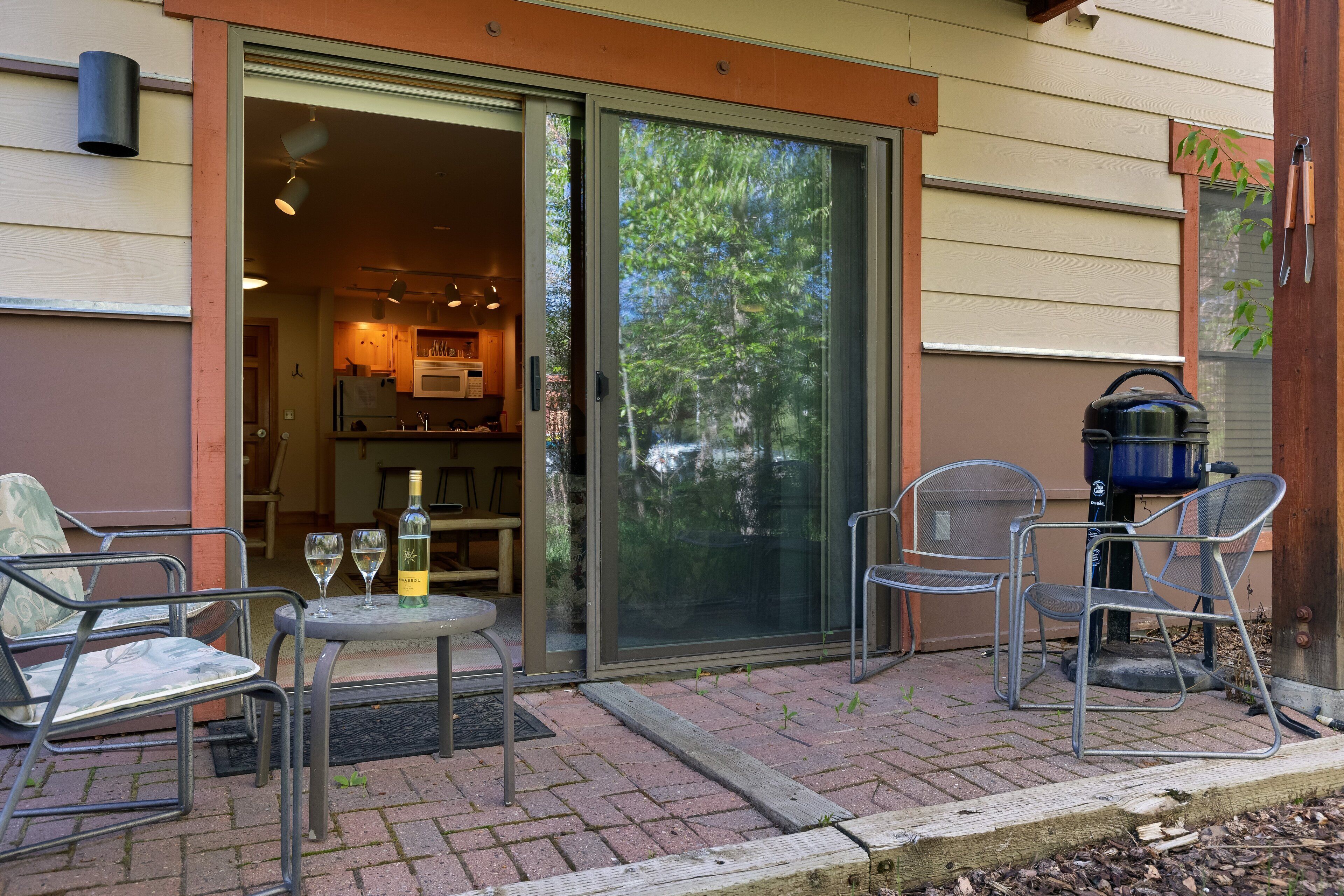 An outdoor patio with a table, chairs, and a grill.