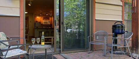 An outdoor patio with a table, chairs, and a grill.