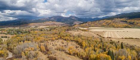 An aerial view of a rural landscape with fields, trees, and mountains in the background.