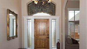 A wooden door with a glass panel, a bench, a chandelier, and a stone arch above. - Teton Harmony (Driggs)