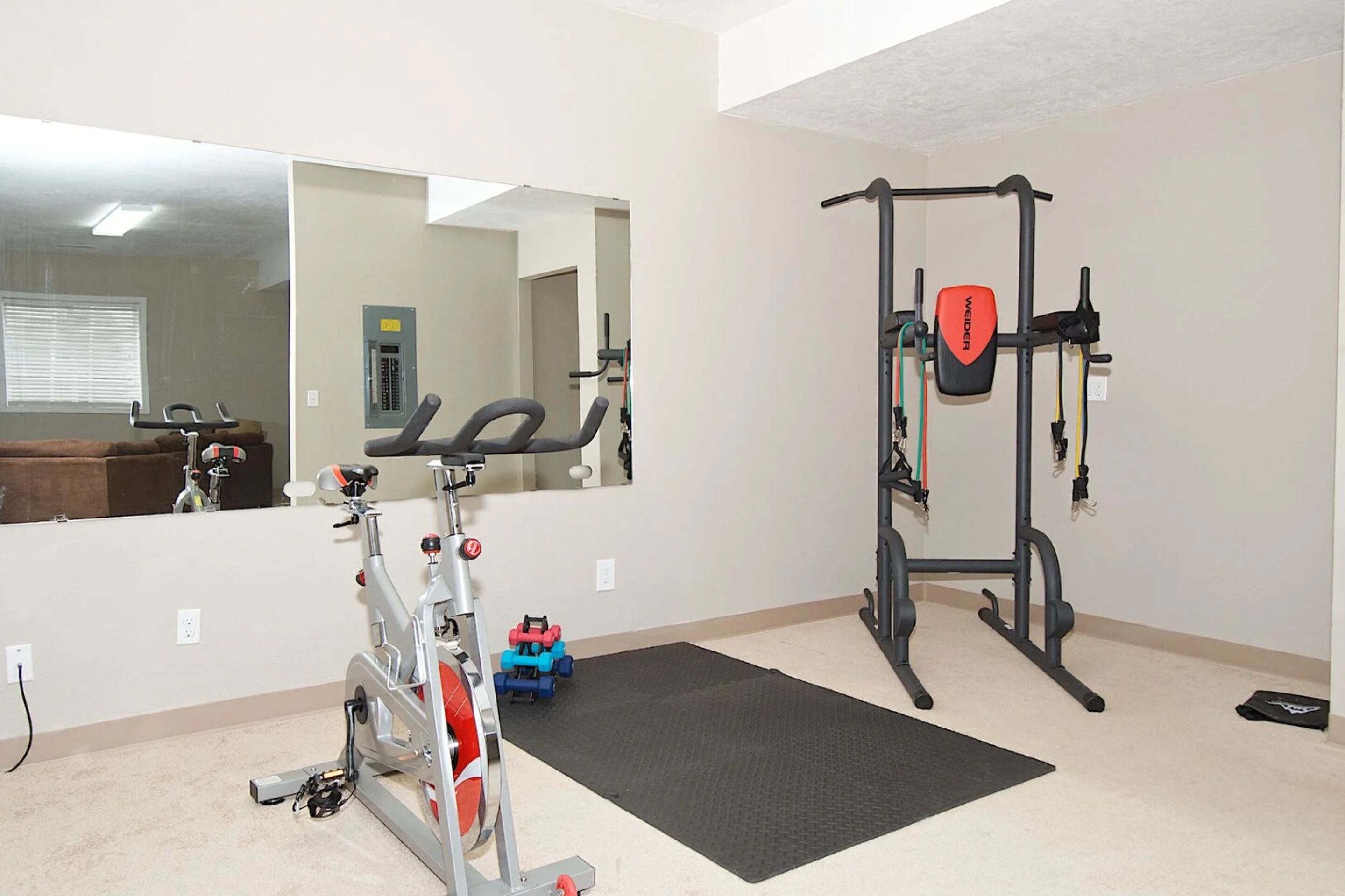 Une salle de sport à domicile équipée d’un vélo d’appartement, d’un banc de musculation et d’une barre de traction.