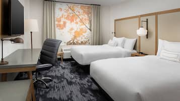 Habitación de hotel con dos camas, un escritorio con silla, televisor y un ventanal con cortinas.