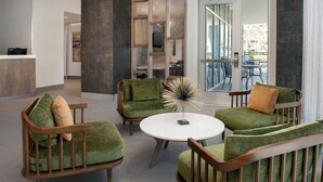 Un área de descanso moderna con sofás tapizados en verde, una mesa redonda blanca y una escultura de vidrio decorativa.
