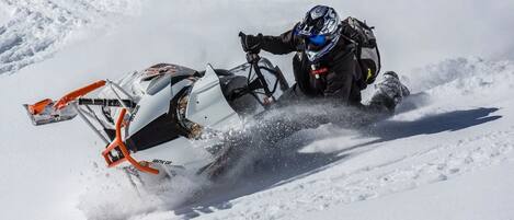 A person riding a snowmobile on a snowy surface.