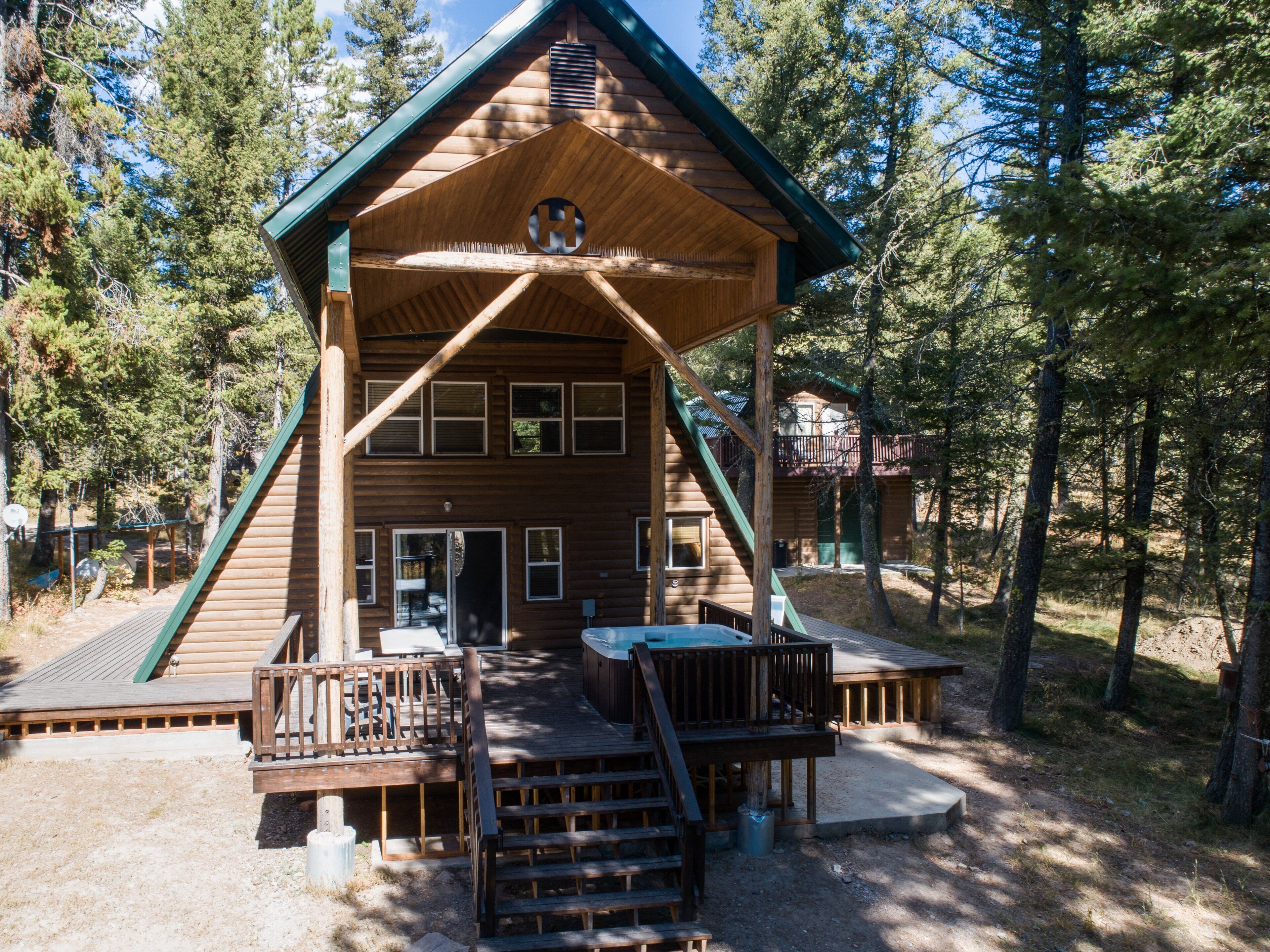 A wooden cabin with a porch, a hot tub, and a deck.