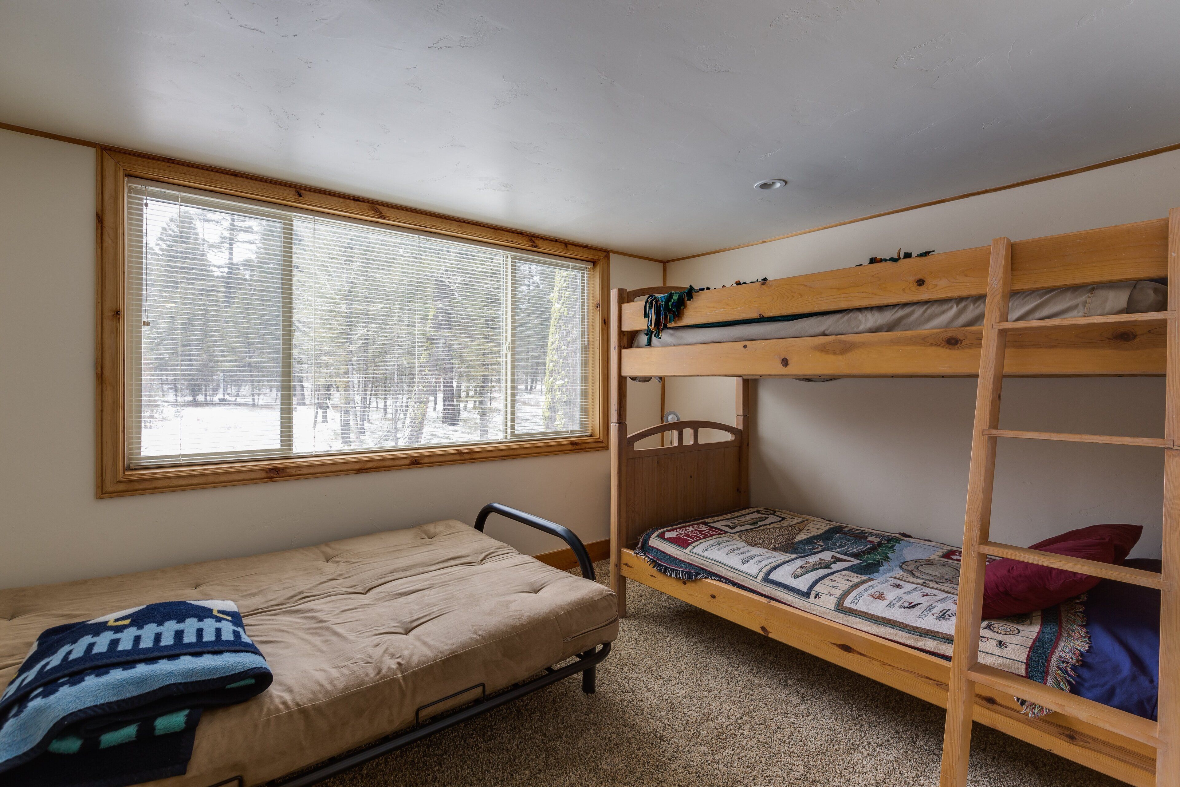 Un dormitorio con una cama individual, una litera y una ventana con persianas.